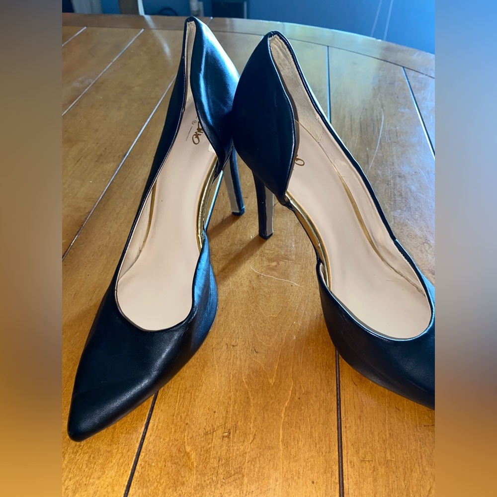 Simple black pointed toe pumps with gold detail.